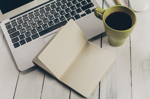A keyboard, notebook and coffee from above